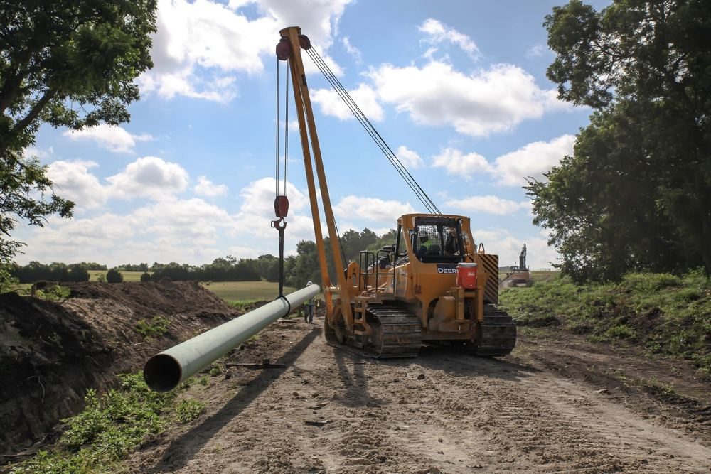 Pipelayer lowering pipe into the ditch