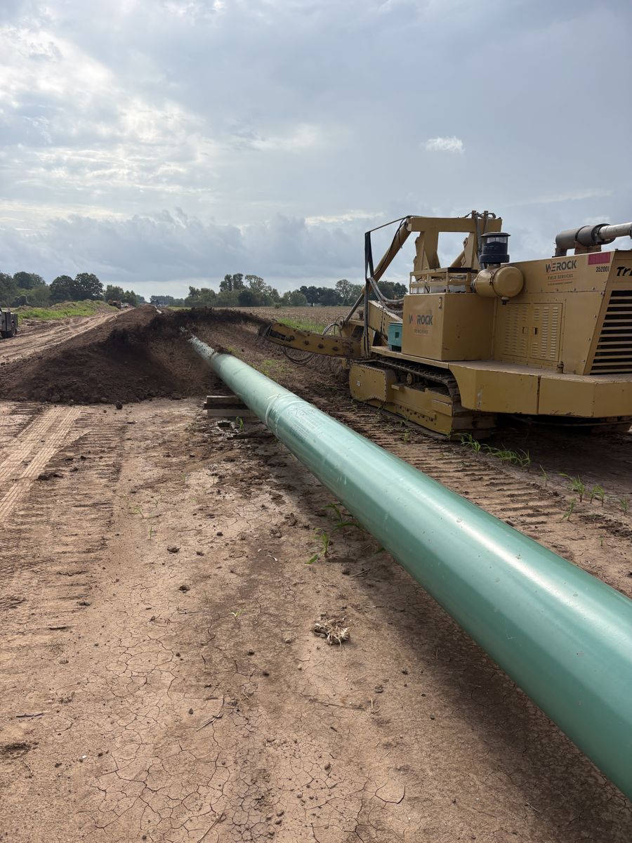 We Rock Trenching trencher cutting ditch beside strung pipe