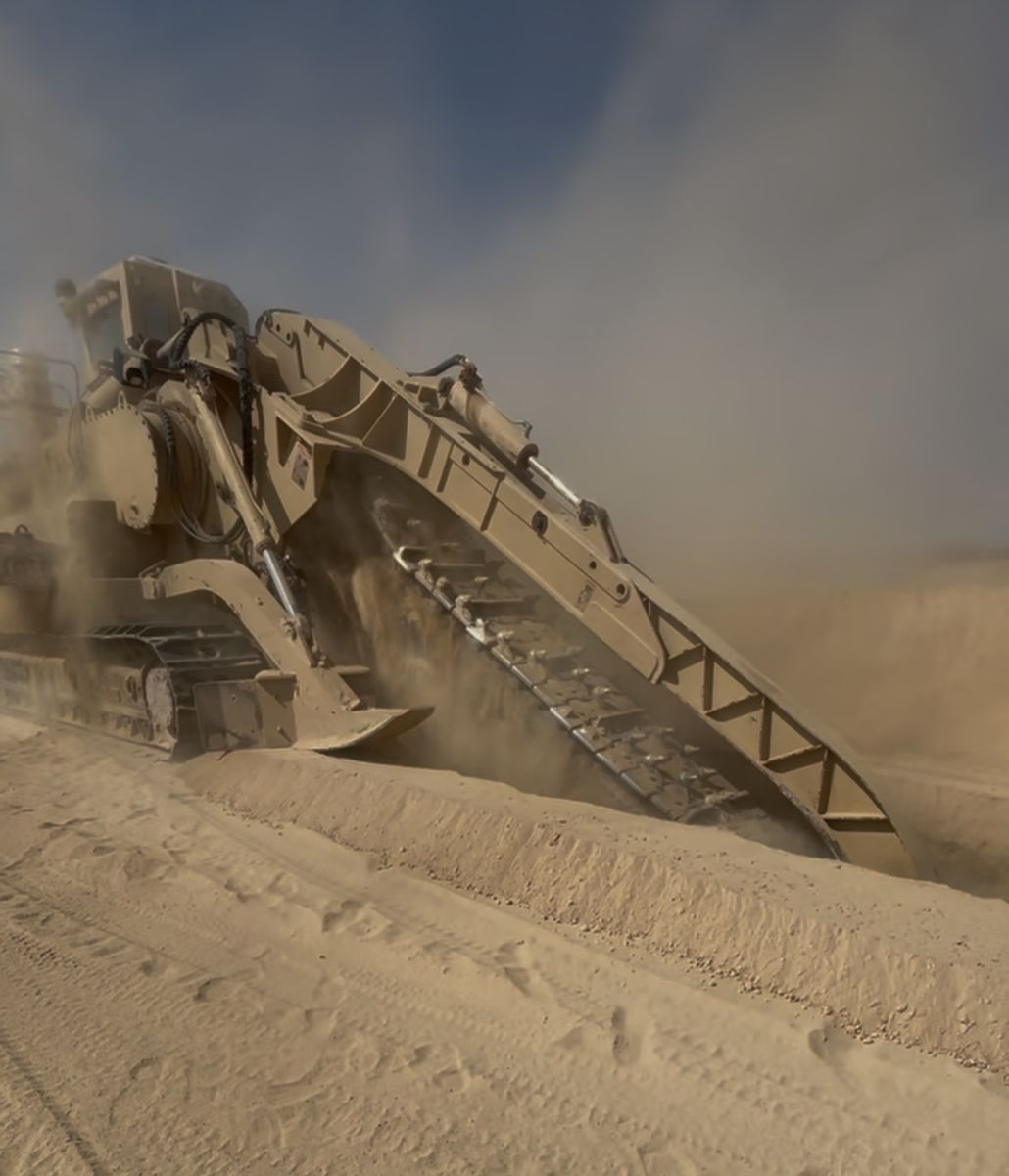 Tesmec M5 rock trencher cutting ditch in a cloud of dust